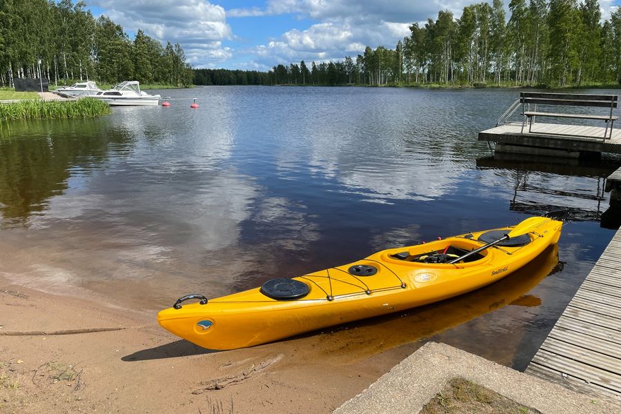 Keltainen kajakki rannassa ja laiturin vieressä